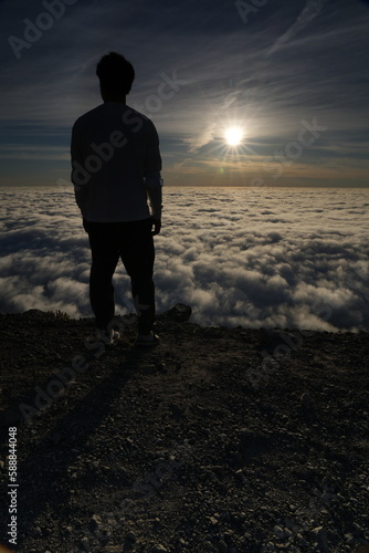 Silhouette of Man Standing on Mountain Above Clouds at Sunrise