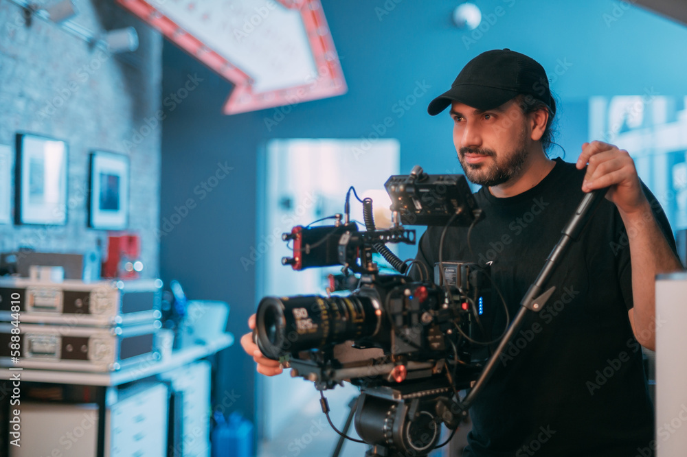 Director of photography with a camera in his hands on the set. Professional videographer at work on filming a movie Director of photography with a camera in his hands on the set. Professional videographer at work on filming a movie