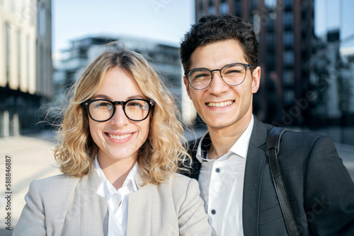 Two colleagues, a woman and a man, persons in business suits, a close portrait smile and show their teeth.
