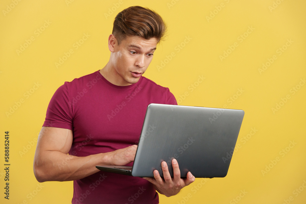 Surprised strong man standing using a laptop Surprised strong man standing using a laptop
