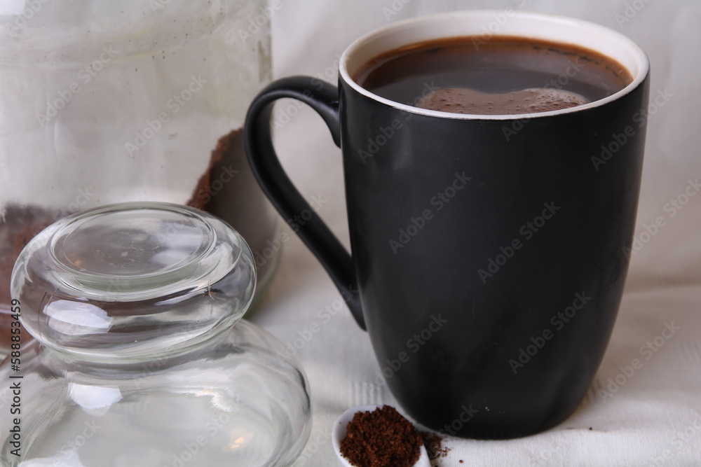 photo black cup with brewed coffee, glass coffee tank and coffee spoon photo black cup with brewed coffee, glass coffee tank and coffee spoon