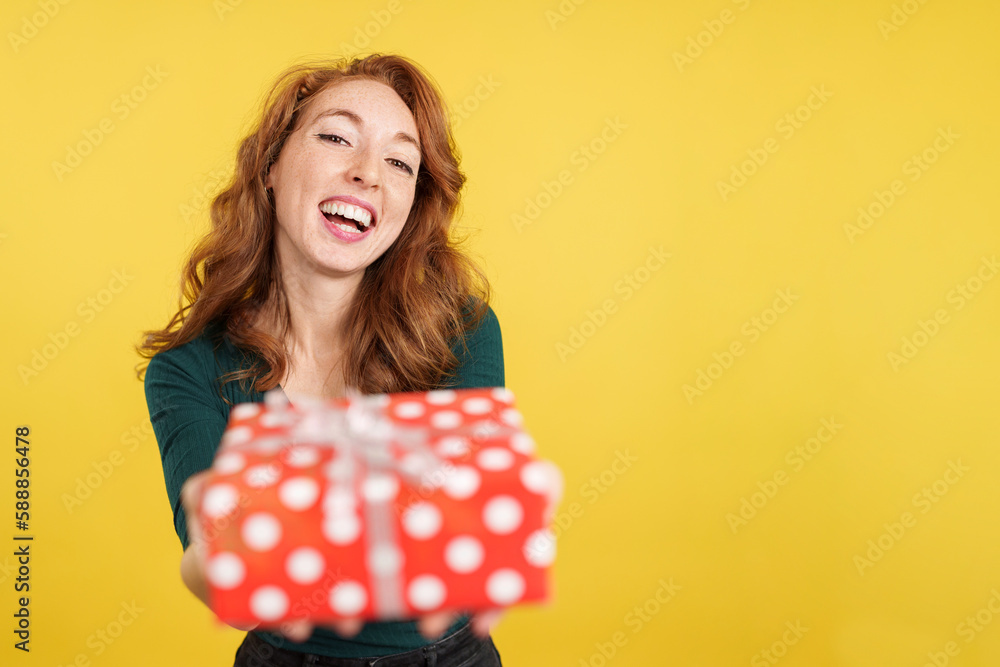 Happy redheaded woman looking at the camera giving a present Happy redheaded woman looking at the camera giving a present