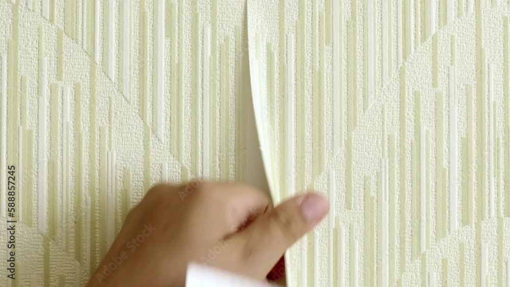 Human hand rip off old yellow wallpaper with scraper from wall and