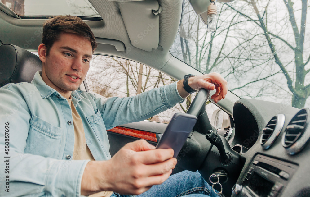 Obraz premium Young man using smartphone in car, Wroclaw, Poland