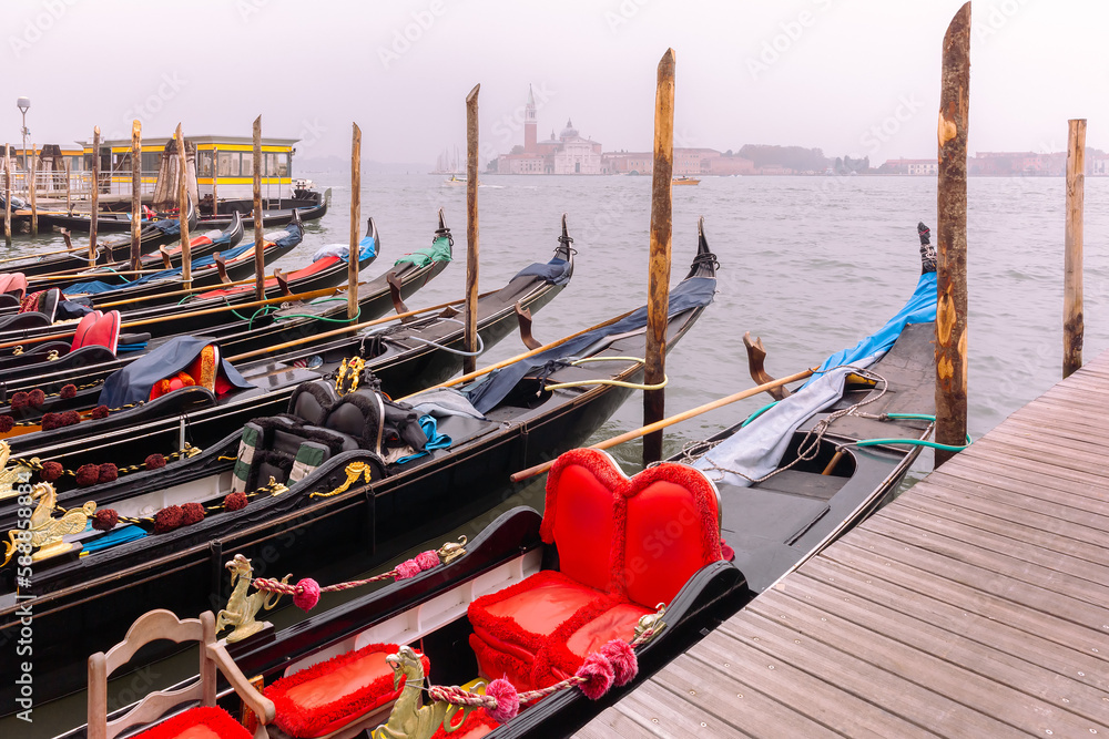 Gondolas moored by Saint Mark square with Church of San Giorgio Maggiore in the background on foggy morning, Venice, Italia