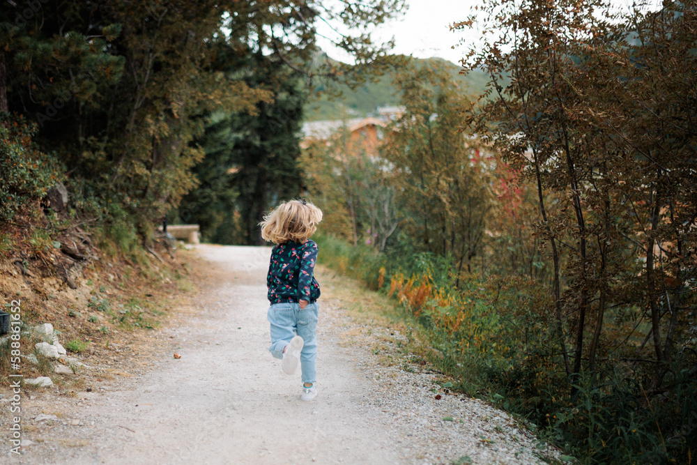 Fototapeta premium petite fille court sur le chemin lors de ses vacances d'été à la montagne