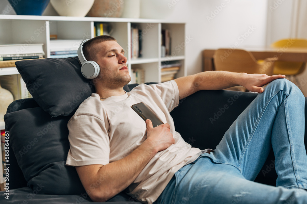 A man is resting on the couch. He fell asleep while listening to music. A man is resting on the couch. He fell asleep while listening to music.