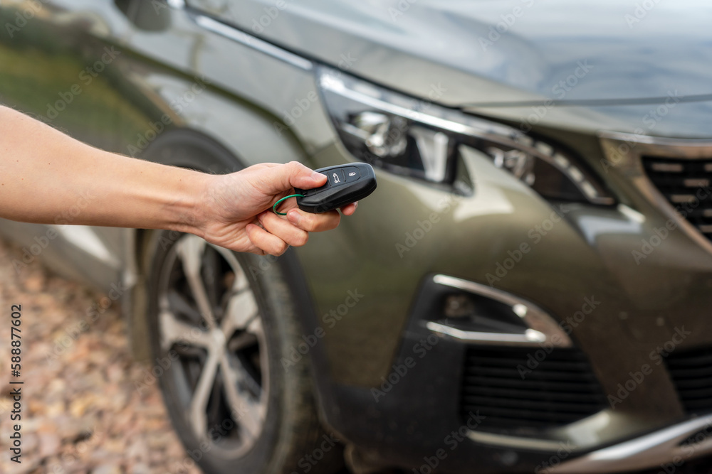 Person holding a car key in the hand stands front car. Insurance, loan and buying car concept Person holding a car key in the hand stands front car. Insurance, loan and buying car concept