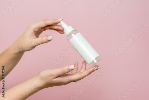 Cosmetic bottle in woman's hands. Cosmetic product branding mockup. Spa beauty treatment concept
