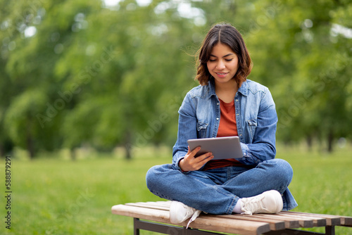 Smiling Young Arab Female Student Resting With Digital Tablet Outdoors