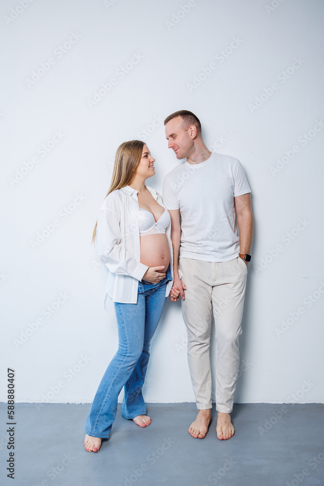 Happy married couple man and pregnant woman on white background in studio a pregnant woman and her husband. A married couple in love Happy married couple man and pregnant woman on white background in studio a pregnant woman and her husband. A married couple in love