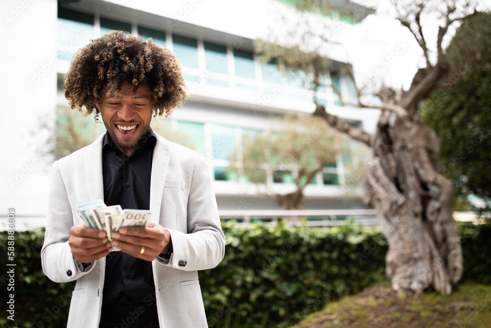 Happy black middle aged businessman holding fan of money, celebrating big financial luck and success, standing outdoors Happy black middle aged businessman holding fan of money, celebrating big financial luck and success, standing outdoors