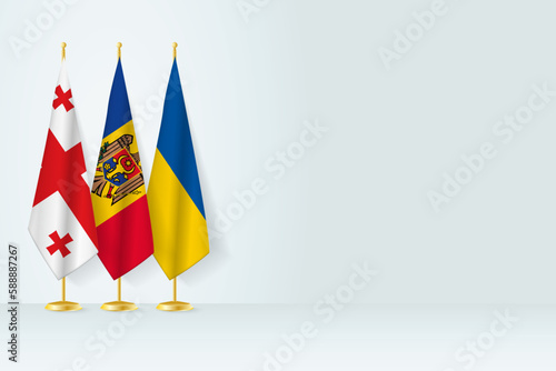 Flags of Georgia, Moldova and Ukraine stand in row on indoor flagpole.
