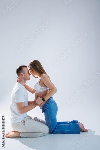 Young happy married couple on a white background in the studio a pregnant woman and her husband
