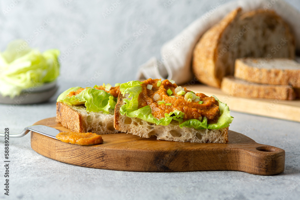 Healthy vegetarian food. Toasted bread sandwich with zucchini caviar, lettuce and green onions on a wooden board. Diet vegan appetizer.