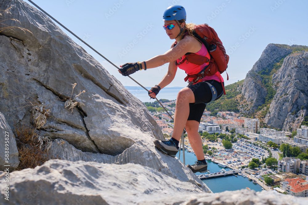 Woman climbs via ferrata Fortica, above Omis city, Croatia, in the Summer. Climber, adventure, active, tourism. activity.