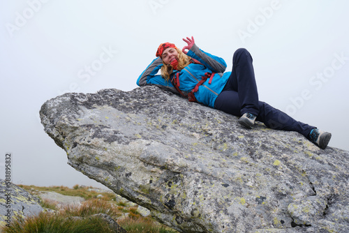 Obraz na płótnie Hiking in Slovakia High Tatras mountains. Woman hiker rests on top of a large rock boulder, laying down, with fog around her. w salonie