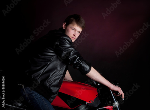 Man, guy in black leather jacket sits on motor bike in studio, motorbike