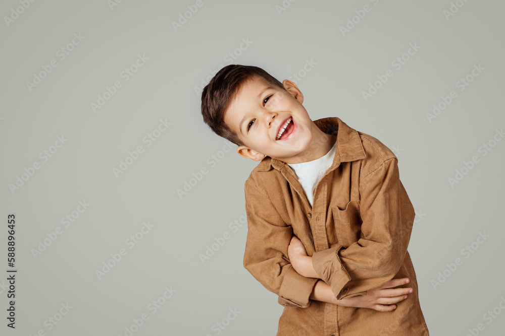 Laughing cute caucasian 6 years old little kid in casual presses hands to belly isolated on gray studio background Laughing cute caucasian 6 years old little kid in casual presses hands to belly isolated on gray studio background