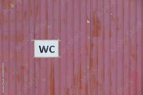 worn board wall with the sign WC printed on a white sheet 