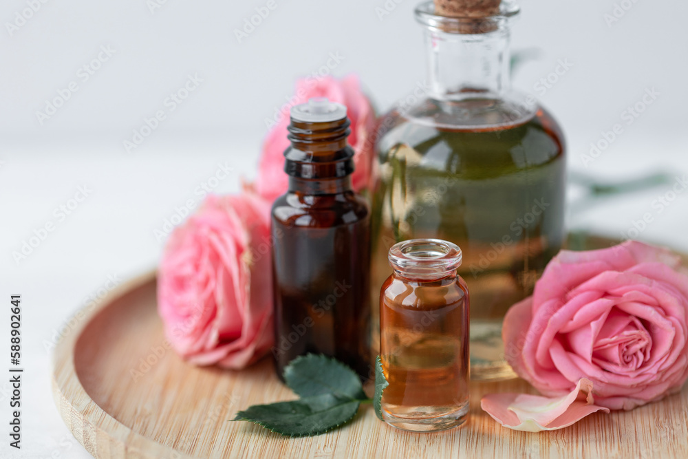 Aromatherapy. Concept of pure organic essential rose oil. Elixir with plant based floral or herbal ingredients. Pink flowers extract. Spa atmosphere with candle, towel. White background Aromatherapy. Concept of pure organic essential rose oil. Elixir with plant based floral or herbal ingredients. Pink flowers extract. Spa atmosphere with candle, towel. White background