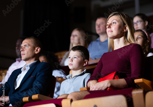 parents with children sitting at premiere in theatrical auditorium