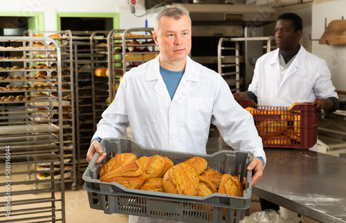 Skilled successful bakers arranging freshly baked bakery products