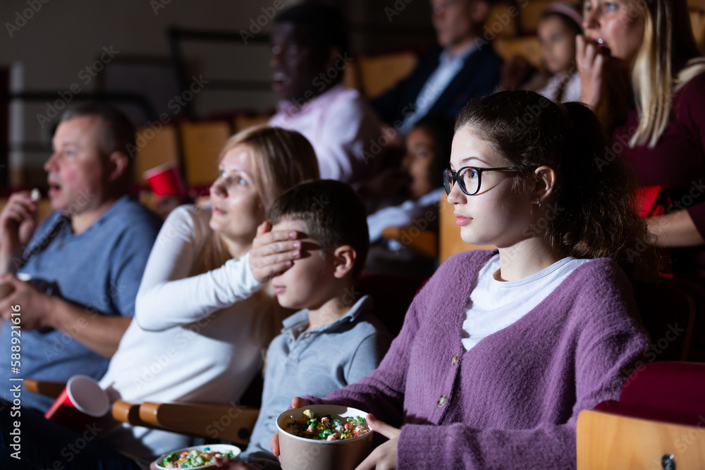 mother, father and their children sitting at horror in auditorium
