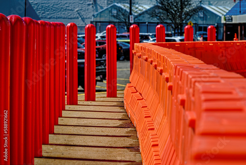 Orange heavy-duty plastic barriers are set up on the sidewalk while construction on the storefront is being done in Vestal in Upstate NY.  Red bollards in a row along the parking lot and sidewalk. © Chet Wiker