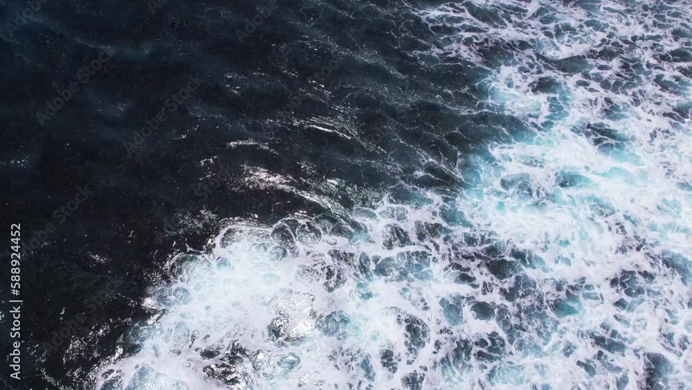 Waves rolling from above. Top down 4k drone view on blue turquoise ocean, slow motion shot. Huge swell hitting shoreline. Bali, Indonesia. Waves rolling from above. Top down 4k drone view on blue turquoise ocean, slow motion shot. Huge swell hitting shoreline. Bali, Indonesia.