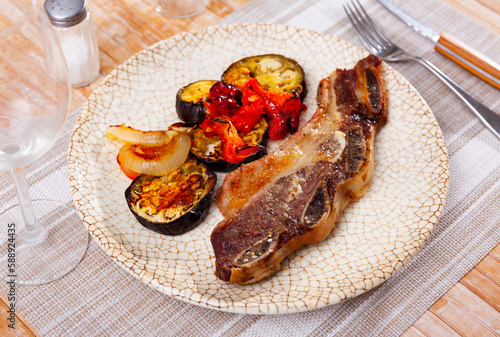 on plate with imitation of antiquity -grilled beef ribs with fried vegetables-aubergine, pepper,onion.Spanish dish-churrasco photo