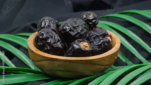 Delicious ajwa dates ( kurma nabi ) or Prophet's Dates. Kurma Ajwa over black fabric texture