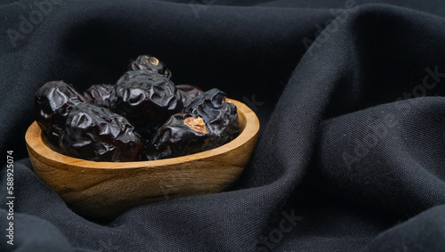Delicious ajwa dates ( kurma nabi ) or Prophet's Dates. Kurma Ajwa over black fabric texture