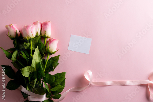 Image of pink tulips with ribbon and card with copy space on pink background