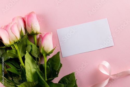 Image of pink tulips with ribbon and card with copy space on pink background
