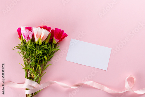 Image of pink and white flowers with ribbon and card with copy space on pink background