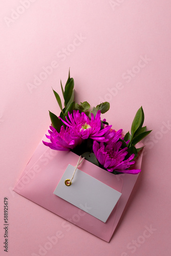 Image of pink flowers in pink envelope with copy space on pink background