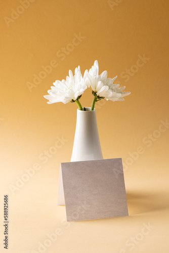 Image of white flowers in white vase and card with copy space on yellow background