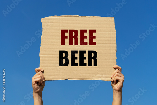 Fotografie Free beer text on box paper held by 2 hands with isolated blue sky background