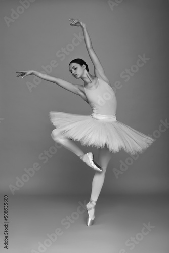 Fototapeta Naklejka Na Ścianę i Meble -  Young ballerina practicing dance moves on light grey background. Black and white effect