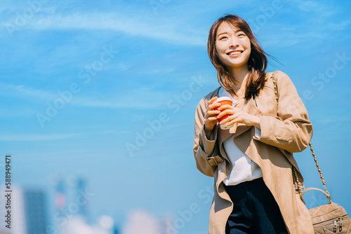 Photographie 青空の都会に立つ笑顔の日本人女性