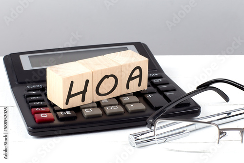 House Models Around HOA concept on wooden cubes on calculator on white background photo