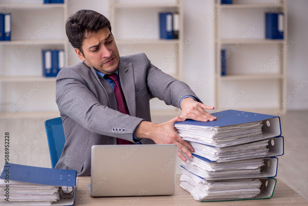Young male employee and too much work in the office Young male employee and too much work in the office