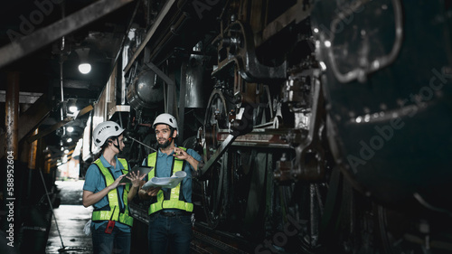 Engineer are working in the factory. Worker helping to repair and inspect the machine's readiness. Mechanical technicians are maintaining the engine in the train garage that is malfunctioning.