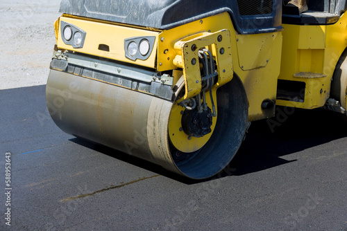 Construction worker in vibratory road roller compactor machine operator laying asphalt