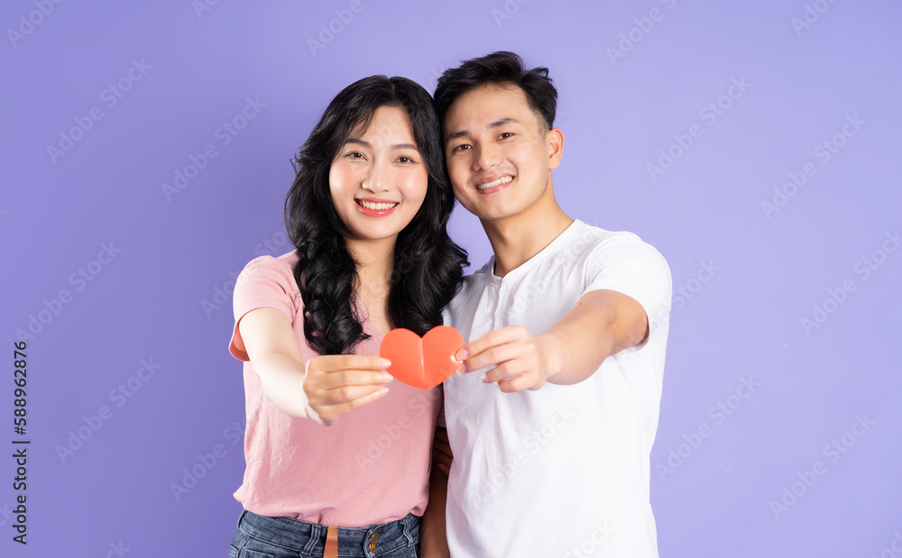 image of asian couple holding a heart sticker, isolated on purple background image of asian couple holding a heart sticker, isolated on purple background