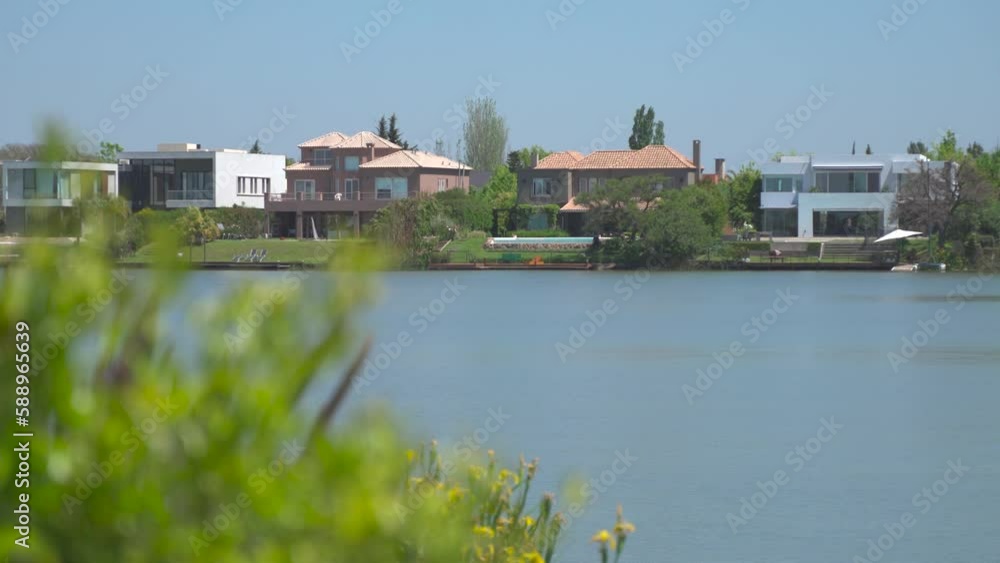 Pan Focus Shot From Green Plant Of Fancy Houses Neighborhood On Quiet Lake Pan Focus Shot From Green Plant Of Fancy Houses Neighborhood On Quiet Lake