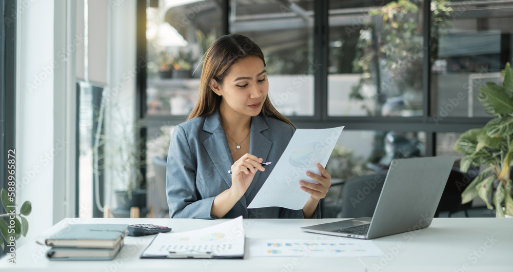 Asian businesswoman sit at their desks and calculate financial graphs showing results about their investments, plan a successful business growth process Asian businesswoman sit at their desks and calculate financial graphs showing results about their investments, plan a successful business growth process