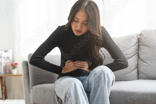 Flatulence asian young woman, girl hand in stomach ache, suffer from food poisoning, abdominal pain and colon problem, gastritis or diarrhoea. Patient belly, abdomen or inflammation, concept.