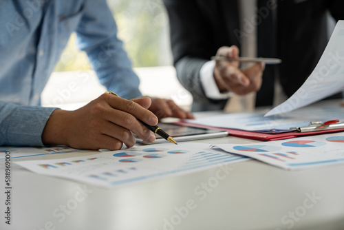 Group of businessmen, investors brainstorming and discussing figures in company financial papers. Financial analyst pointing to data graph to check account meeting concept.
